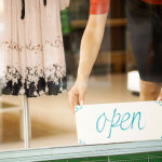 Boutique-salesperson-placing-open-sign-in-the-window
